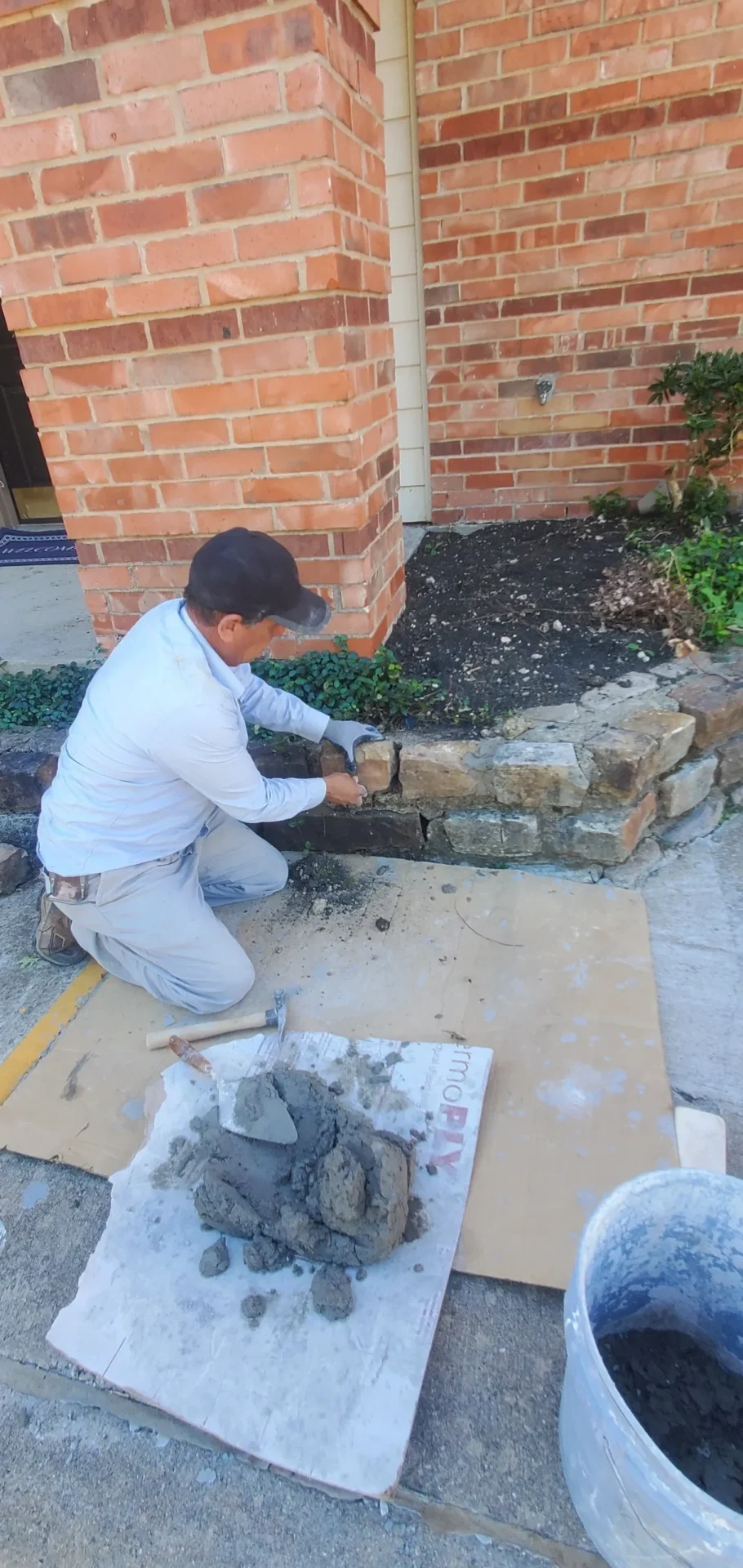 A man is working on the side of a brick wall.